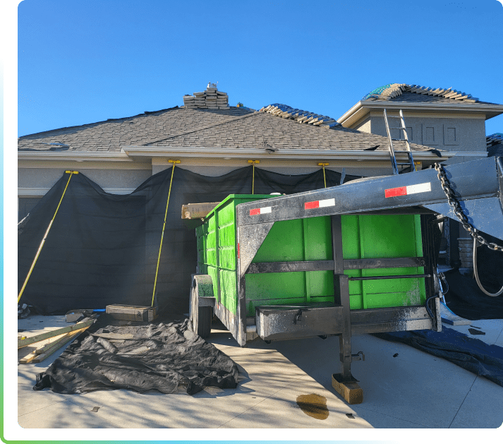 A dumpster is being loaded onto the roof of a house.